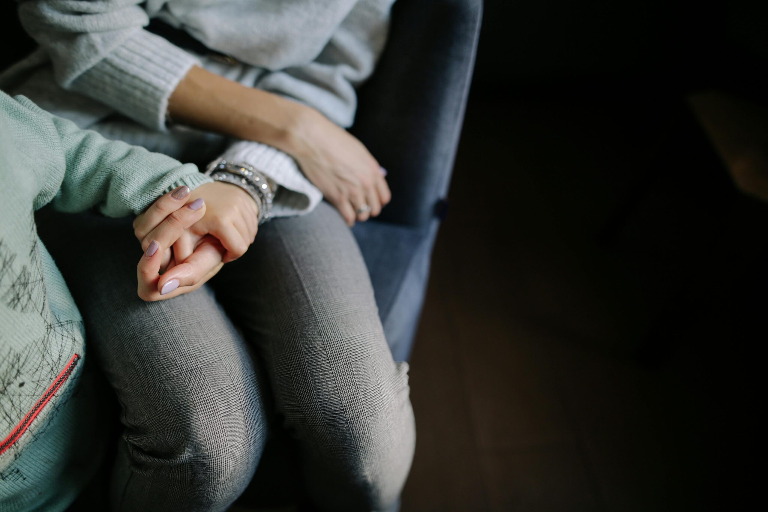 A close-up of a mother and child holding hands while seated together, conveying warmth and connection.