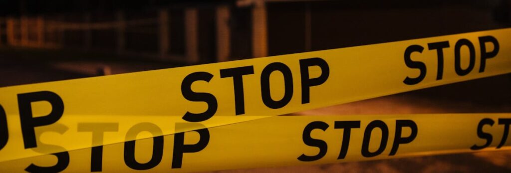 Yellow stop tape blocking a residential street at night, creating a restricted area.