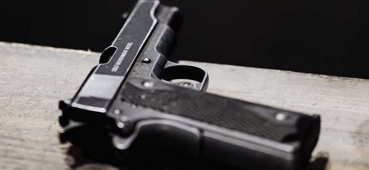 Detailed shot of a pistol placed on a wooden surface in an indoor setting.
