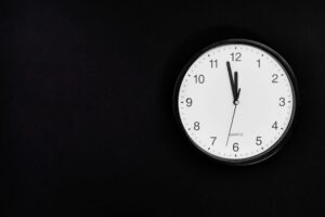 A simple wall clock set at midnight on a black background, ideal for business or time-related concepts.